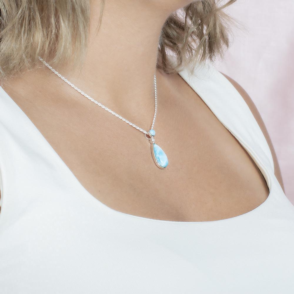 The picture shows a model wearing a 925 sterling silver larimar teardrop pendant with topaz.