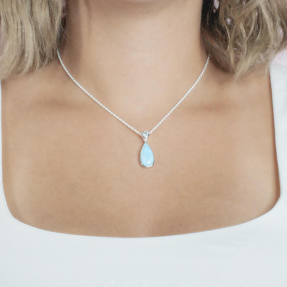 The picture shows a model wearing a 925 sterling silver larimar teardrop pendant with aquamarine and cubic zirconia.