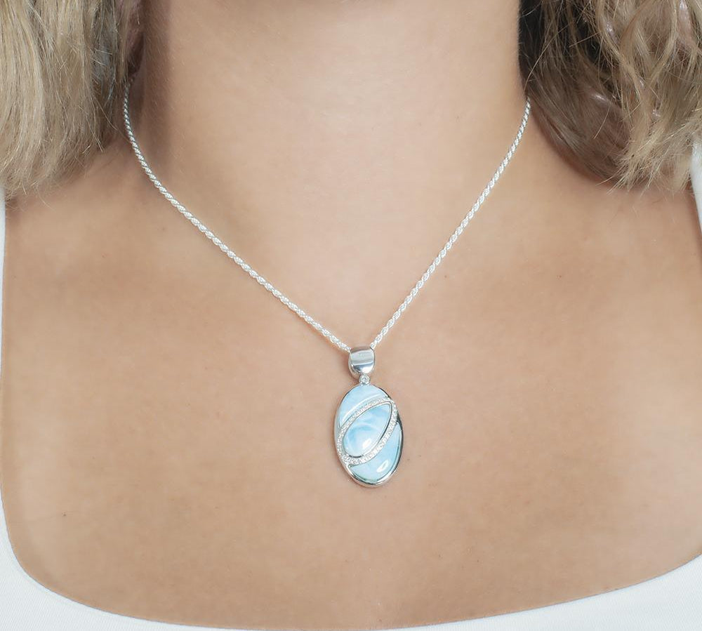 The picture shows a model wearing a 925 sterling silver larimar pendant with aquamarine and topaz.