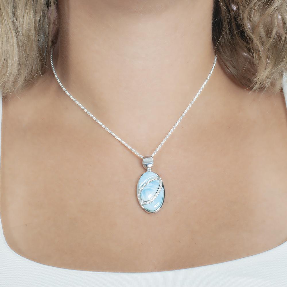 The picture shows a model wearing a 925 sterling silver larimar pendant with aquamarine and topaz.