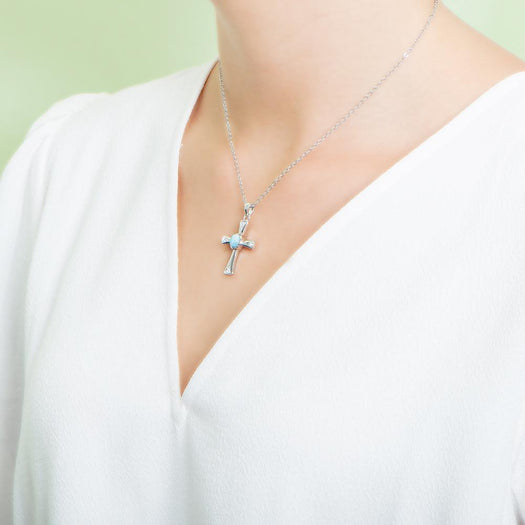 The picture shows a model wearing a 925 sterling silver larimar centered cross pendant.