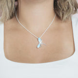 In this photo there is a model with blonde hair and a white shirt, wearing a sterling silver dragonfly pendant with blue larimar gemstones.