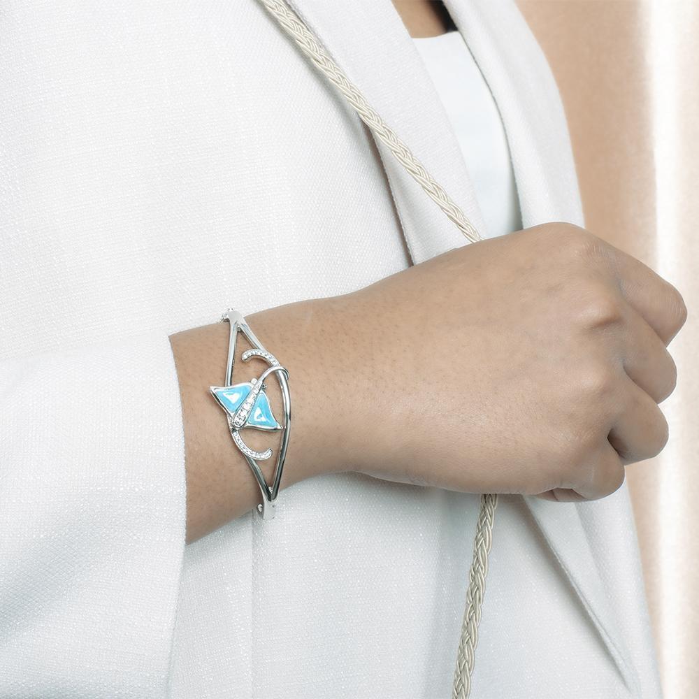 The picture shows a model wearing a 925 sterling silver larimar eagle ray bangle with topaz.