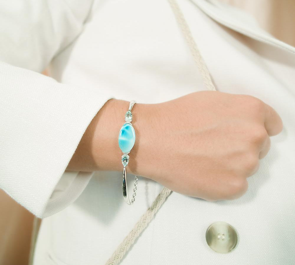 The picture shows a model wearing a 925 sterling silver larimar eclipse bracelet with topaz bracelet with aquamarine.