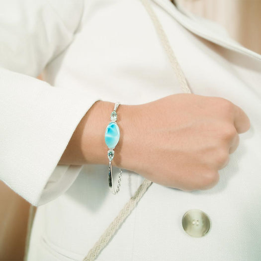 The picture shows a model wearing a 925 sterling silver larimar eclipse bracelet with topaz bracelet with aquamarine.