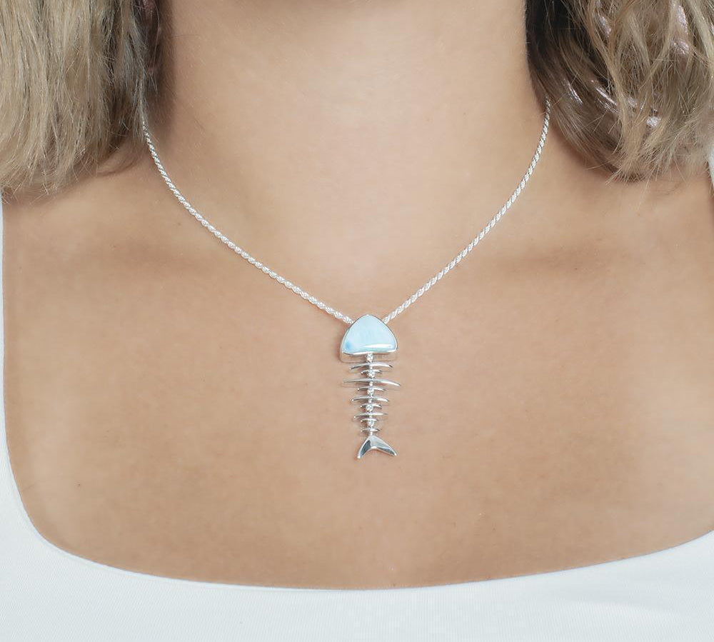 The picture shows a mode wearing a 925 sterling silver larimar fish bone pendant with cubic zirconia.