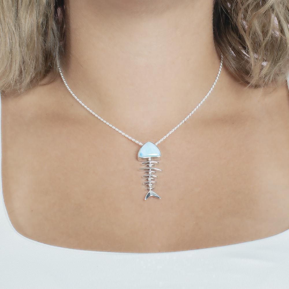 The picture shows a mode wearing a 925 sterling silver larimar fish bone pendant with cubic zirconia.