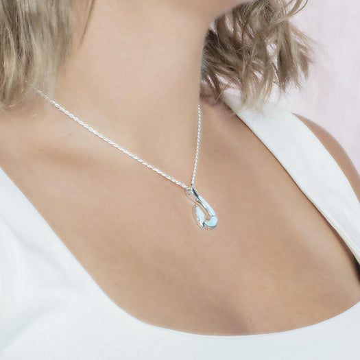 In this photo there is a model with blonde hair and a white shirt turned to the right, wearing a sterling silver fish hook pendant with blue larimar gemstones.