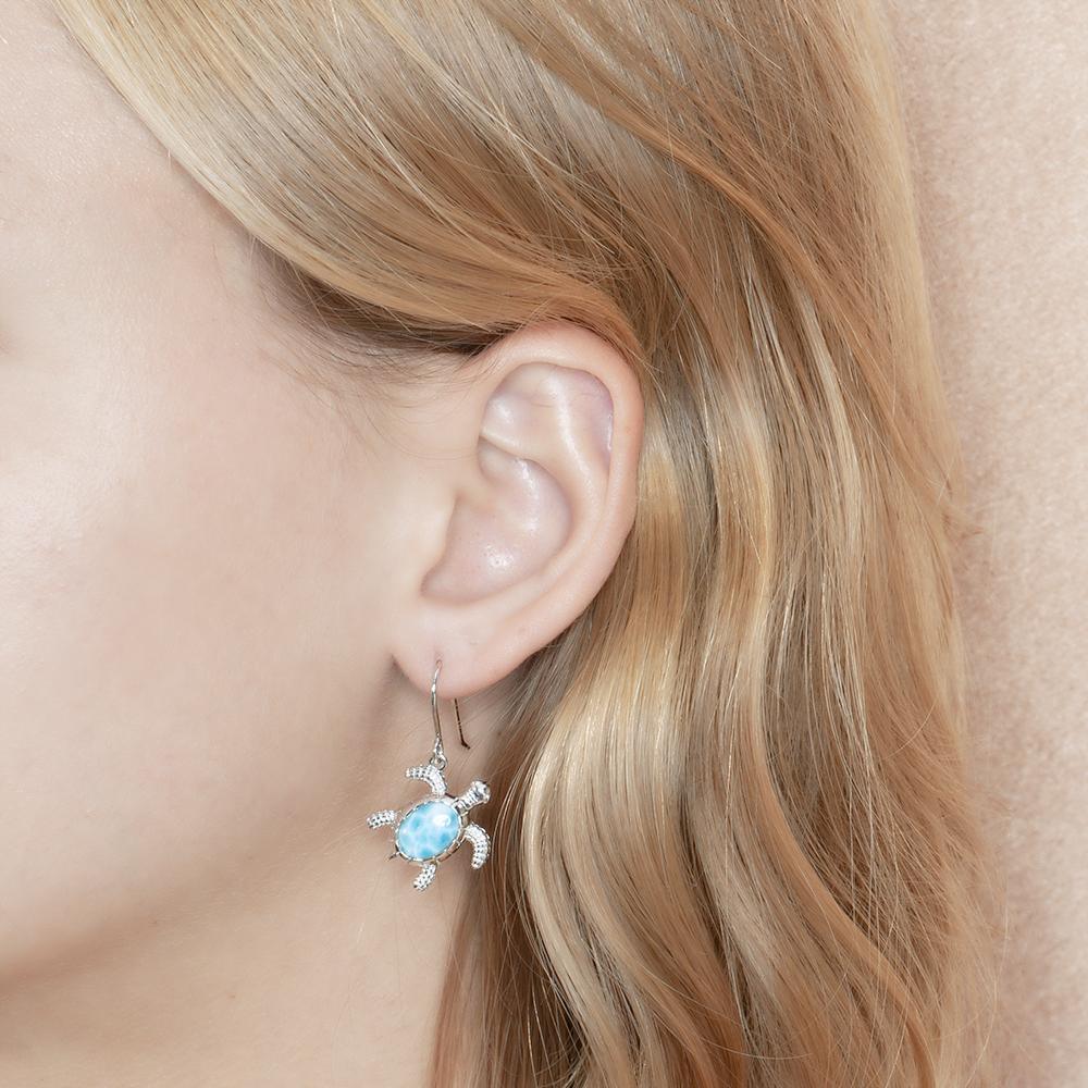 The picture shows a model wearing a 925 sterling silver larimar turtle hook earring.
