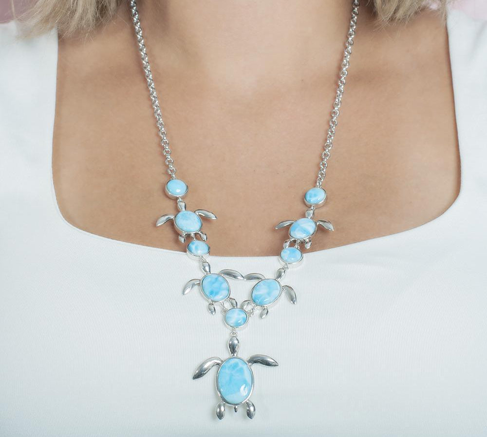 The picture shows a model wearing a 925 sterling silver larimar sea turtle charm necklace.