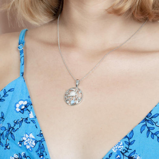 The picture shows a model wearing a 925 sterling silver one stone larimar sea turtle pendant with larimar gemstones and topaz.