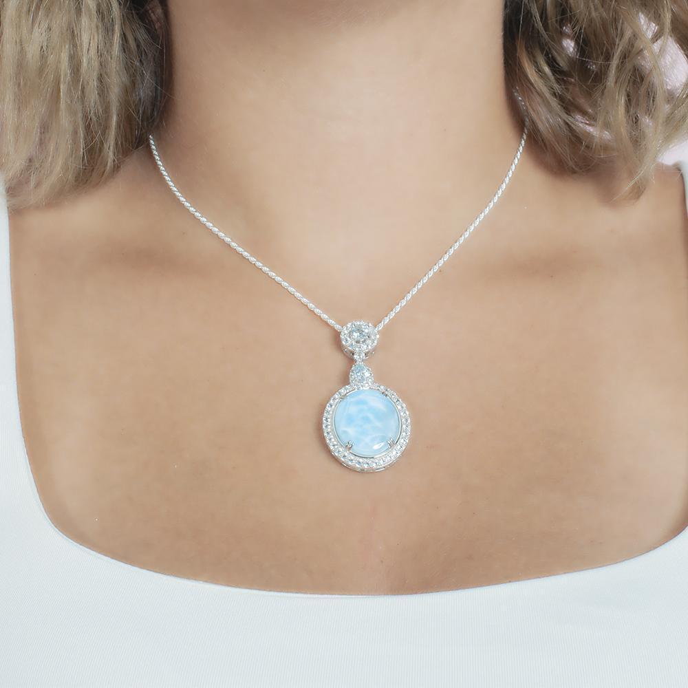 The picture shows a model wearing a 925 sterling silver larimar mirror pendant with topaz and sapphire.