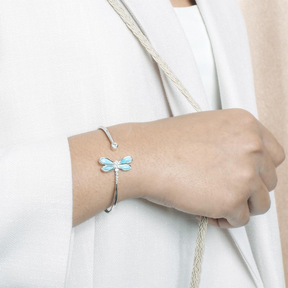In this photo there is a model wearing a 925 sterling silver dragonfly bangle with blue larimar and aquamarine gemstones.