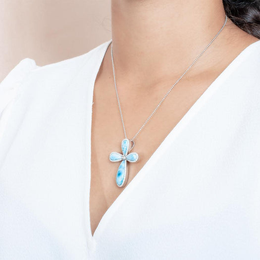 The picture shows a model wearing a 925 sterling silver larimar cross pendant with topaz.