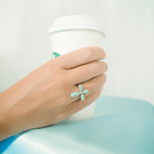The picture shows a model wearing a 925 sterling silver larimar cross ring paired with topaz.