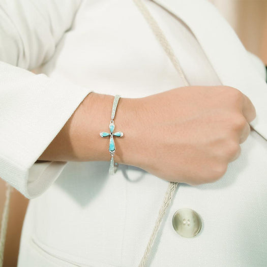 The picture shows a model wearing a 925 sterling silver larimar cross bracelet with topaz.