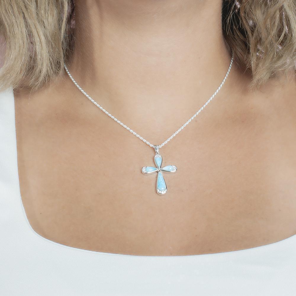 The picture shows a model wearing a 925 sterling silver larimar cross pendant with topaz.
