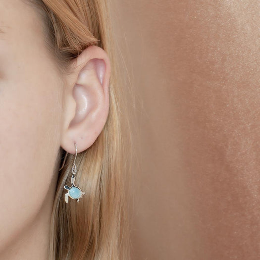 The picture shows a model wearing a 925 sterling silver larimar sea turtle hook earring.