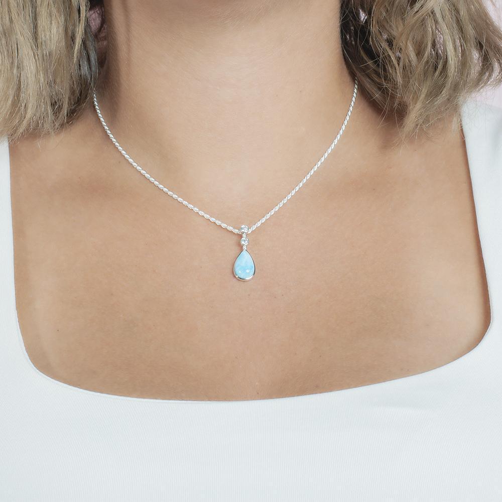 The picture shows a model wearing a 925 sterling silver larimar teardrop pendant with topaz.