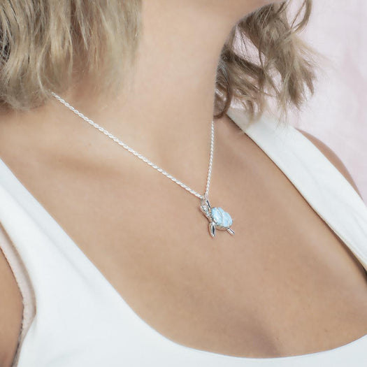 The picture shows a model wearing a 925 sterling silver larimar sea turtle pendant with topaz.
