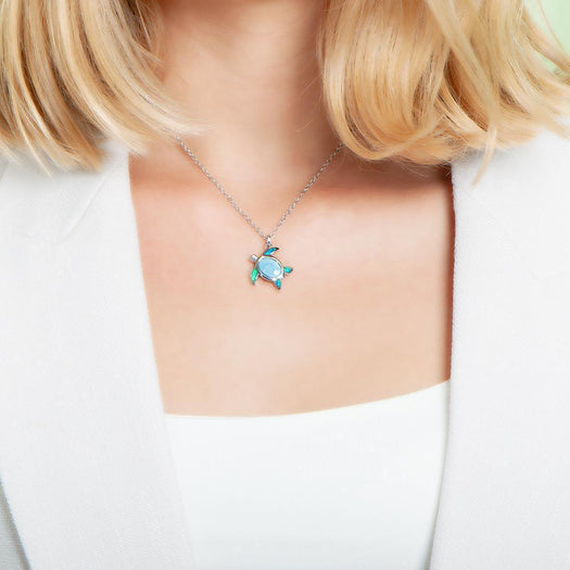 The picture shows a model wearing a 925 sterling silver sea turtle pendant with one larimar gemstone and four opalite.