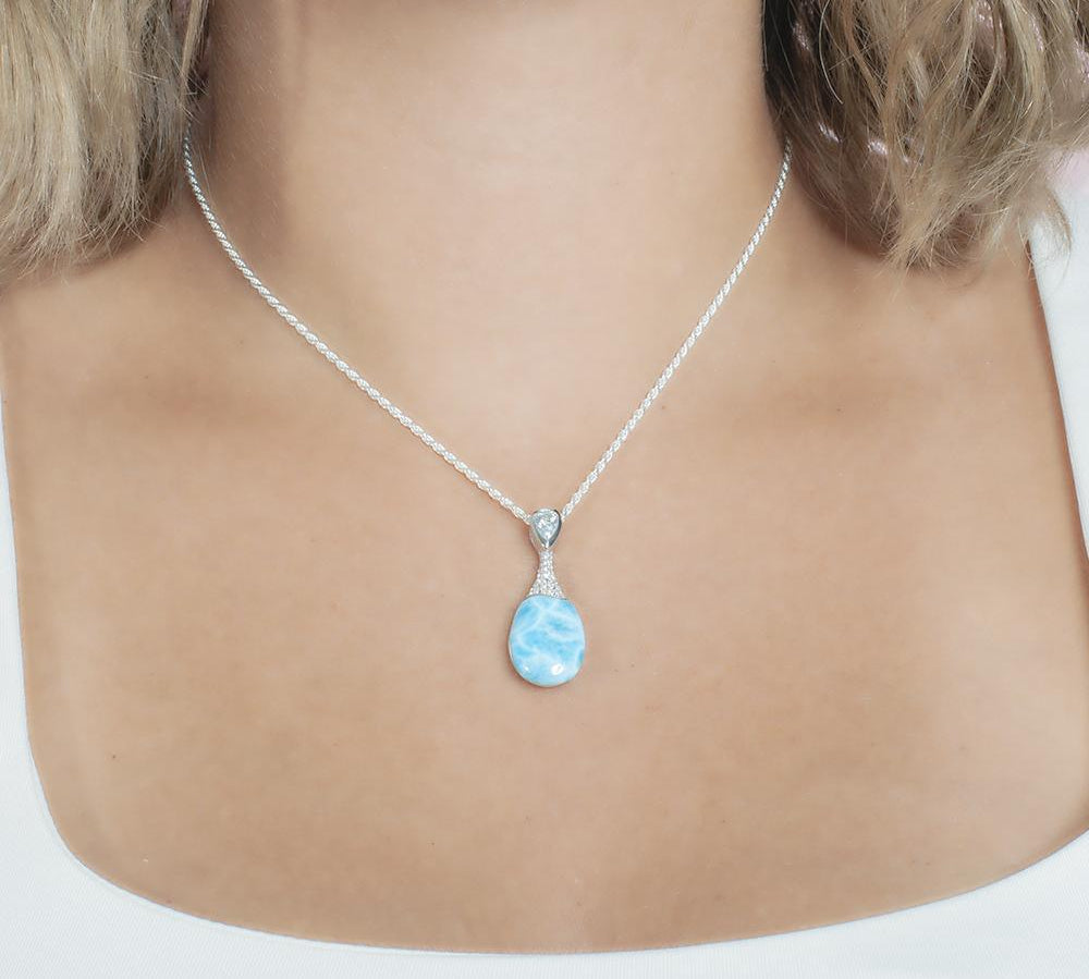 The picture shows a model wearing a 925 sterling silver larimar love potion bottle pendant with aquamarine and topaz.