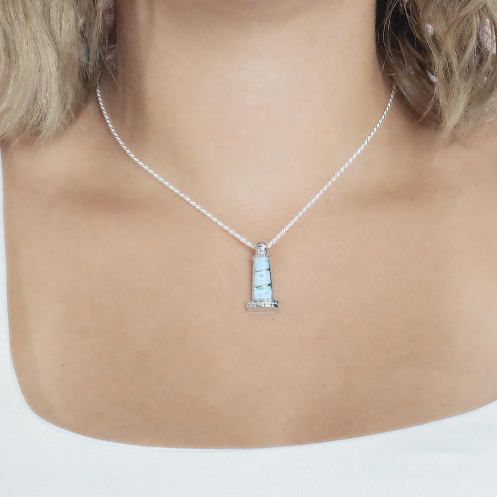 In this picture there is a model with blonde hair and a white shirt wearing a lighthouse pendant with blue larimar gemstones set in sterling silver.