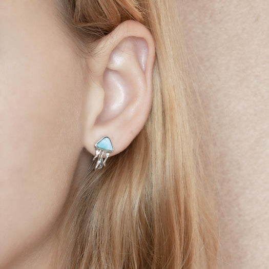 The picture shows a model wearing a 925 sterling silver larimar moon jellyfish stud earring.