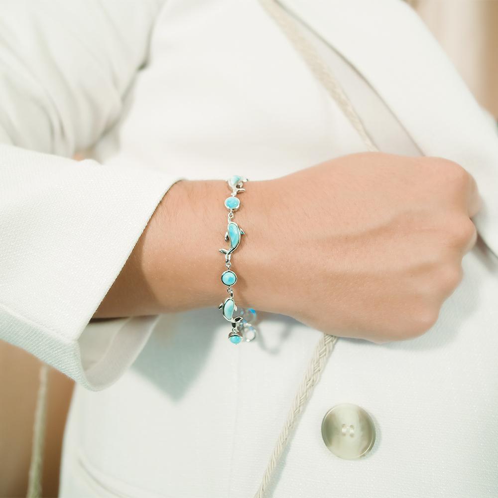 The picture shows a model wearing a 925 sterling silver larimar dolphin bracelet.