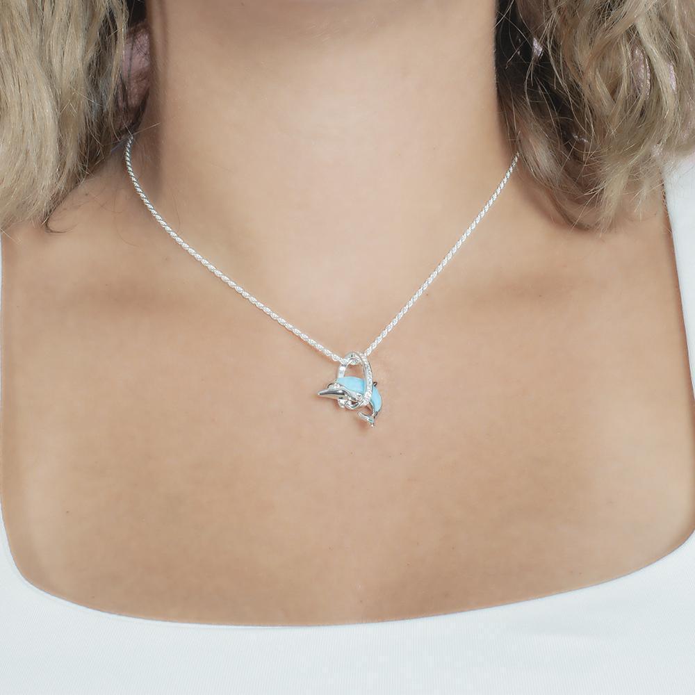 The picture shows a model wearing a 925 sterling silver larimar dolphin through circle pendant with topaz.