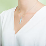 The picture shows a model wearing a 925 sterling silver larimar bar pendant.