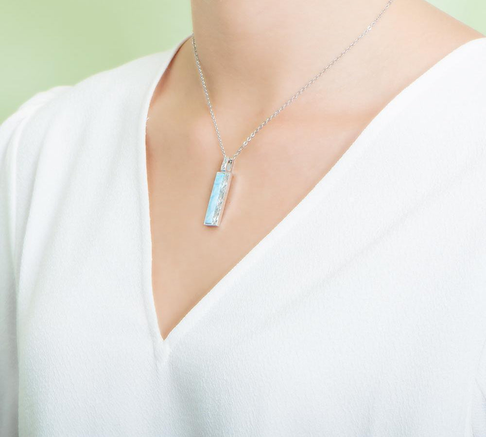 The picture shows a model wearing a 925 sterling silver larimar bar pendant.