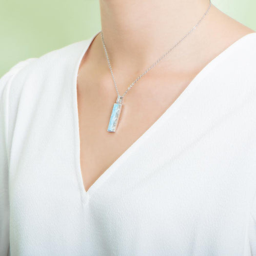 The picture shows a model wearing a 925 sterling silver larimar bar pendant.