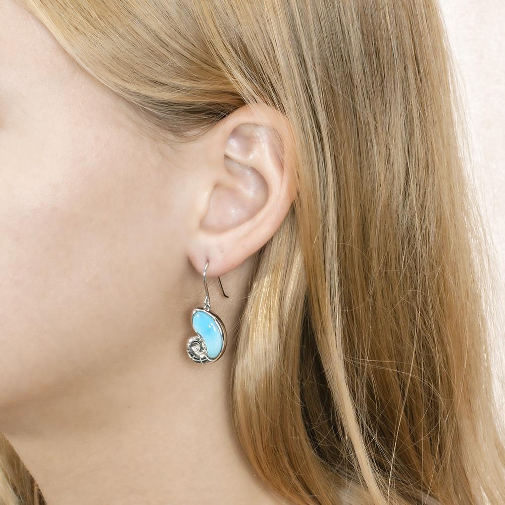 The picture shows a model wearing a 925 sterling silver larimar shell hook earring.