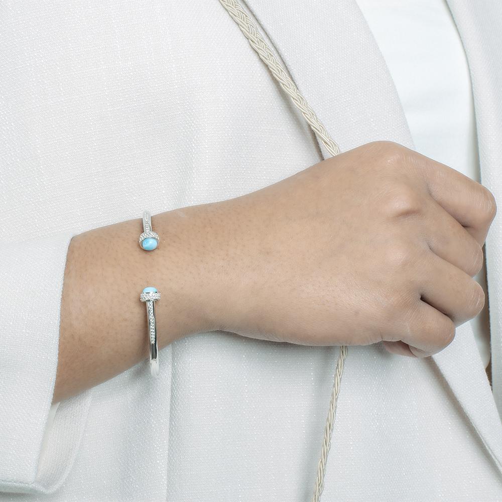 The picture shows a model wearing a 925 sterling silver larimar bangle with topaz.