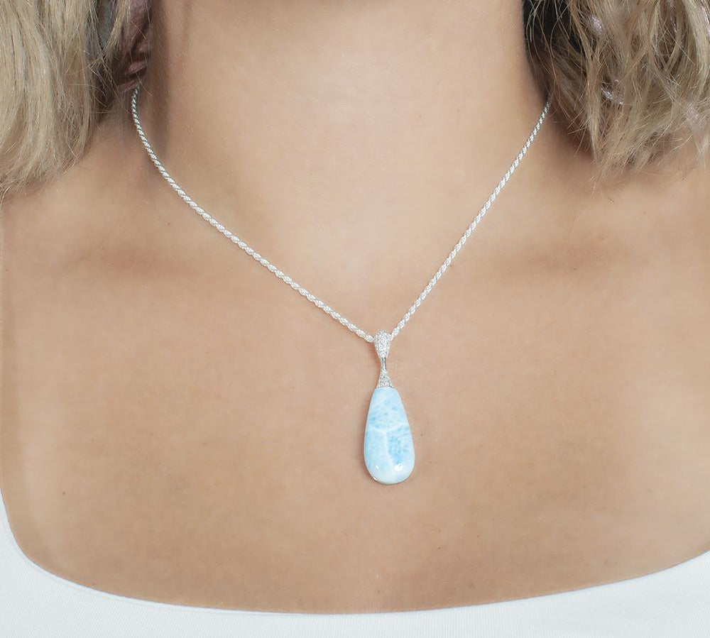 The picture shows a model wearing a 925 sterling silver larimar teardrop pendant with topaz.