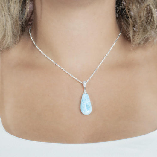 The picture shows a model wearing a 925 sterling silver larimar teardrop pendant with topaz.