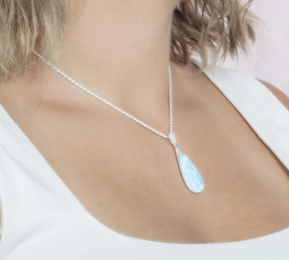 The picture shows a model wearing a 925 sterling silver larimar teardrop pendant with topaz.