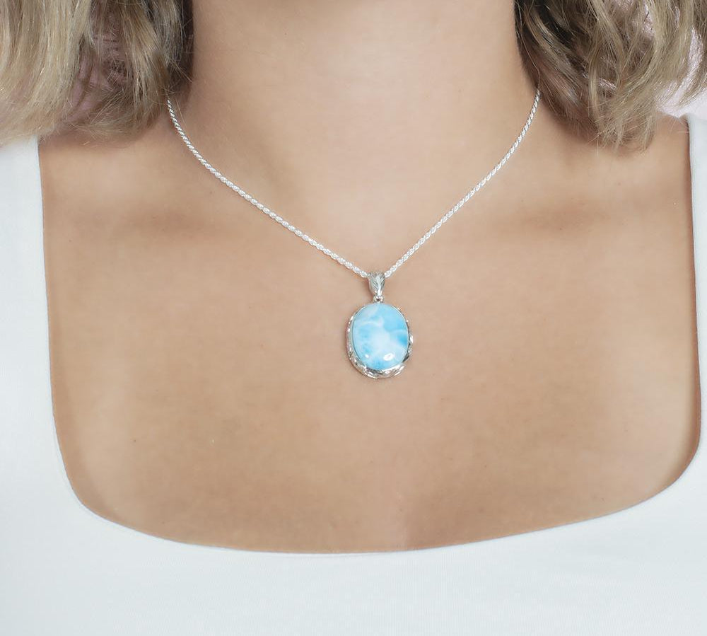 The picture shows a model wearing a 925 sterling silver oval larimar pendant with hand engravings.