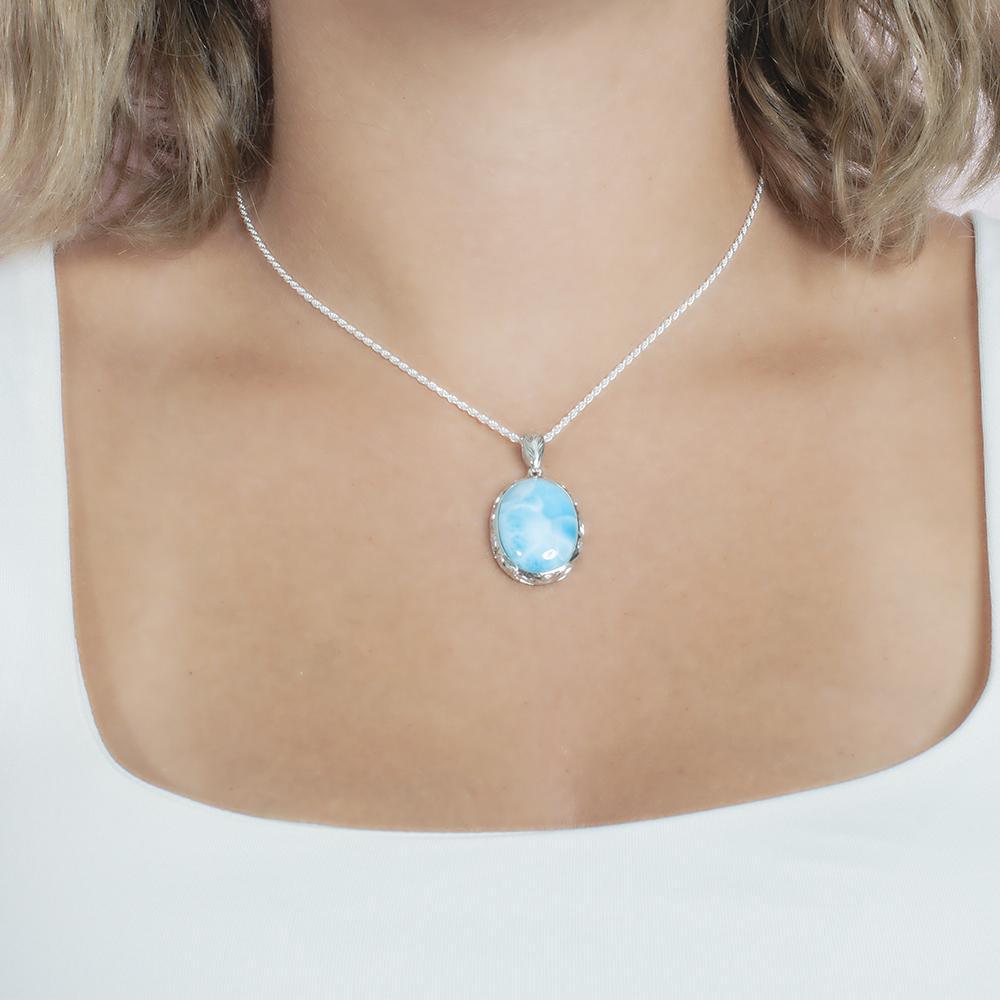 The picture shows a model wearing a 925 sterling silver oval larimar pendant with hand engravings.