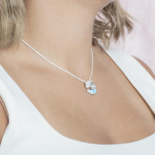 The picture shows a model wearing a 925 sterling silver larimar ocean wave pendant with topaz.