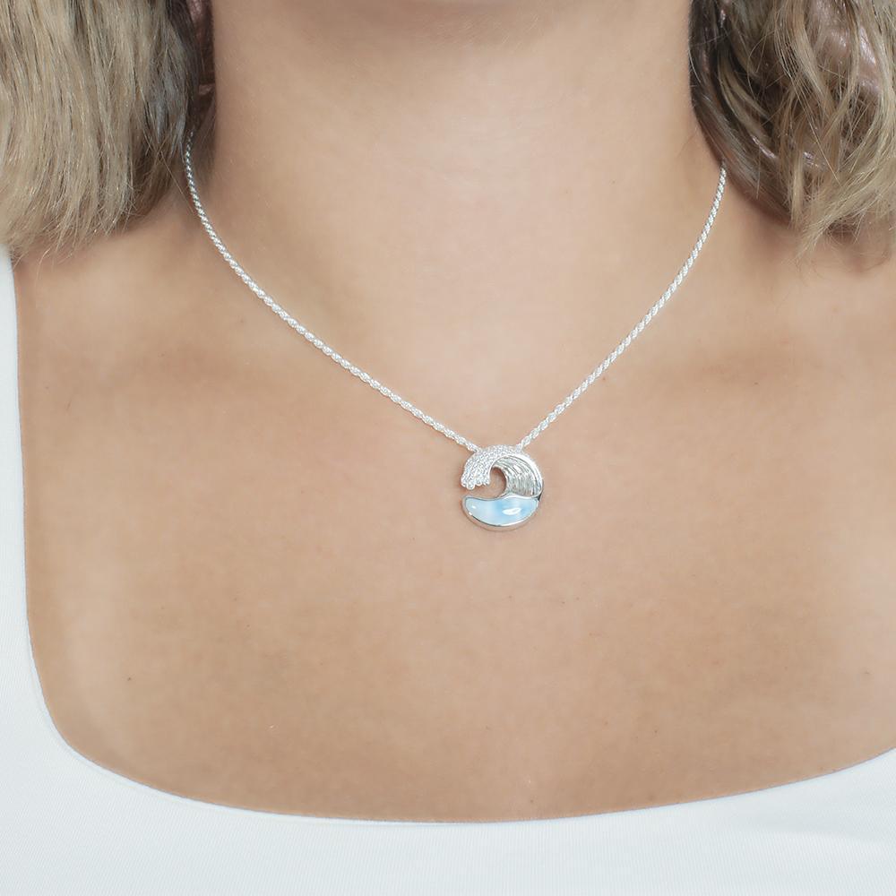 The picture shows a model wearing a 925 sterling silver larimar ocean wave pendant with topaz.