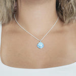 The picture shows a model wearing a 925 sterling silver larimar and opalite circle pendant.