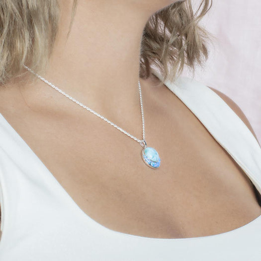 The picture shows a model wearing a 925 sterling silver larimar and opalite circle pendant.
