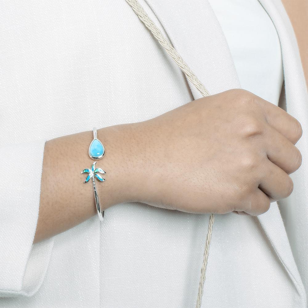 This photo shows a model wearing a 925 sterling silver larimar teardrop and opalite palm tree banle