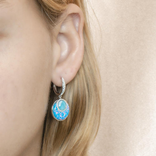 The picture shows a model wearing a 925 sterling silver larimar and opalite lever-back earrings