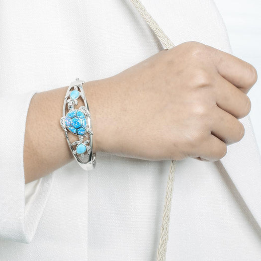 The picture shows a model wearing a 925 sterling silver larimar and opalite 3 sea turtle bangle.