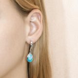 This image has a model wearing a 925 sterling silver larimar and opalite oval dangle earring