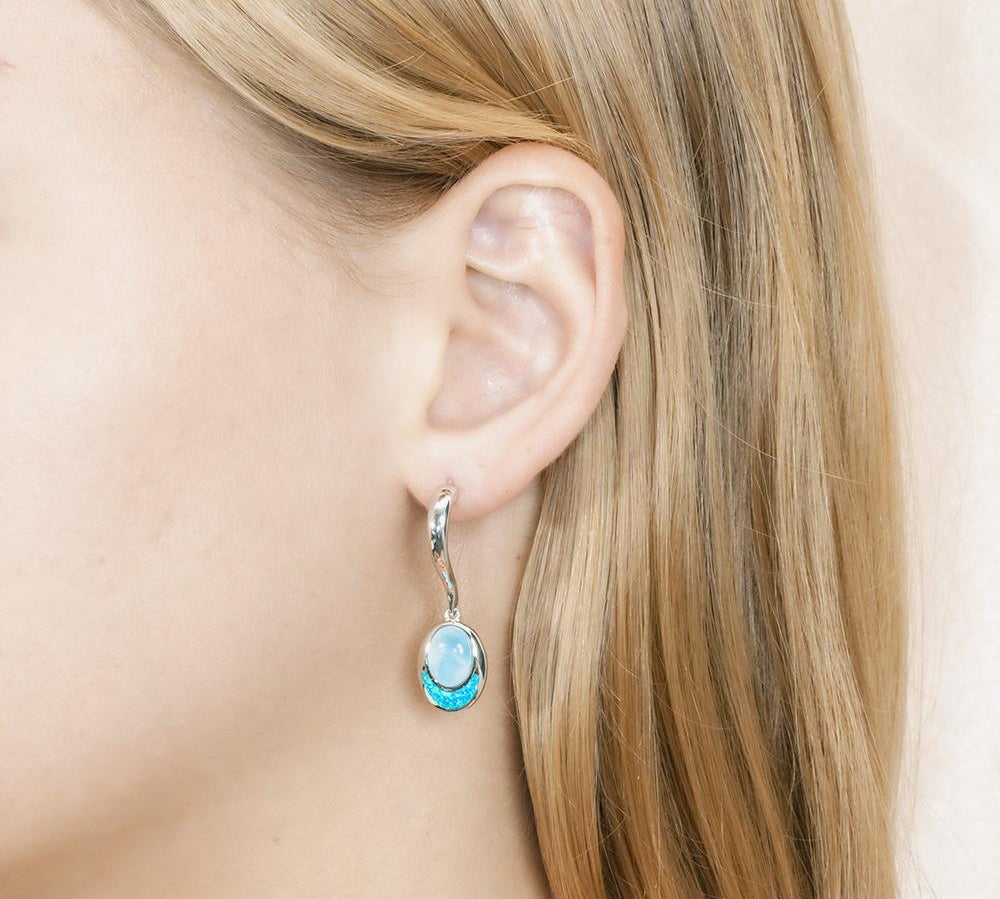 This image has a model wearing a 925 sterling silver larimar and opalite oval dangle earring