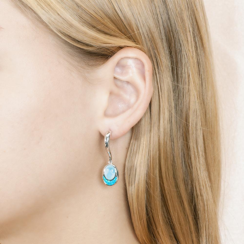 This image has a model wearing a 925 sterling silver larimar and opalite oval dangle earring